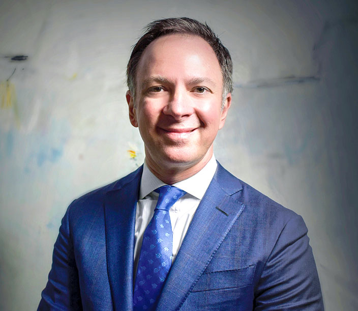 Dr. Andres Bustillo in a blue suit, offering expert advice on post-surgery travel safety before flying.