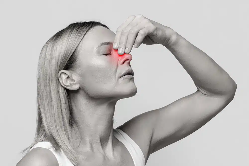 Woman with highlighted nose swelling touches her bridge, symbolizing  healing.