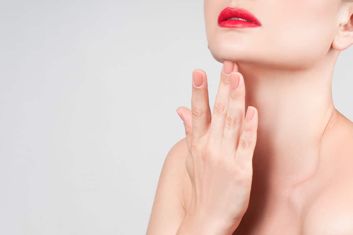 Close-up of elegant jawline with focus on graceful neck and red lips.