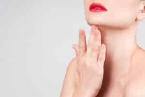 Close-up of elegant jawline with focus on graceful neck and red lips.