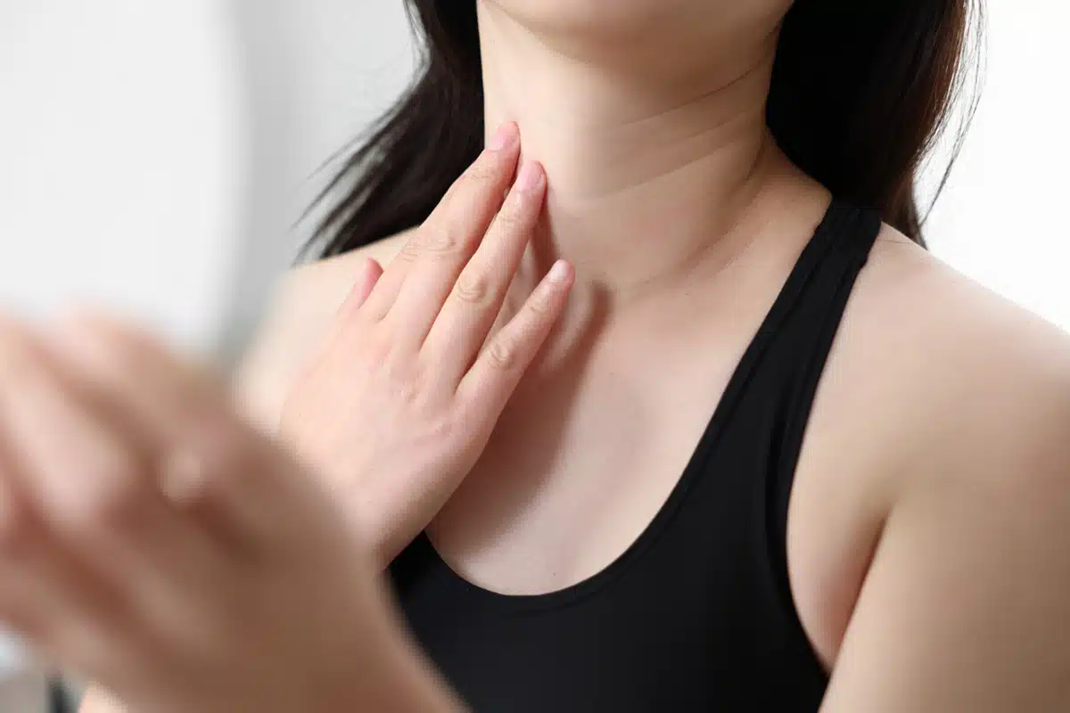 Close-up of a woman touching her smooth neck, indicative of laser neck lift results.