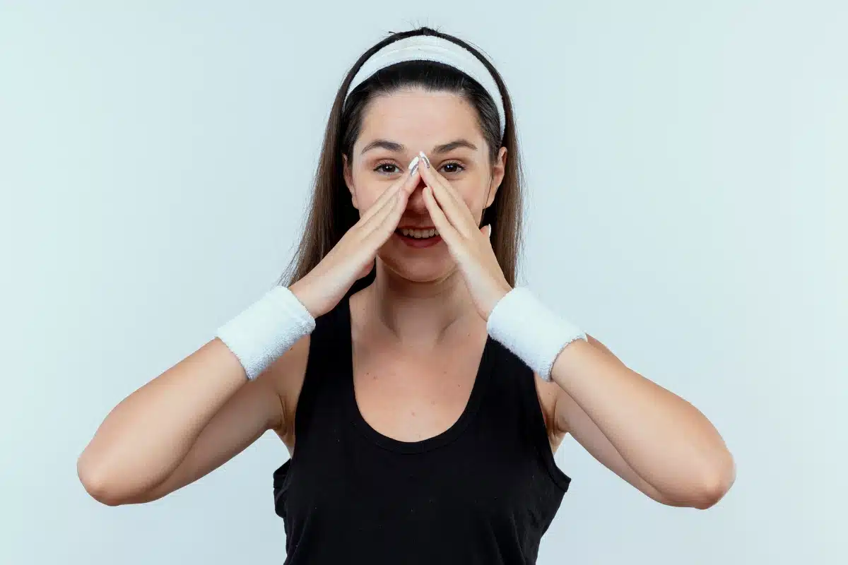 Woman gesturing towards nose, symbolizing before revision rhinoplasty for nose lengthening.