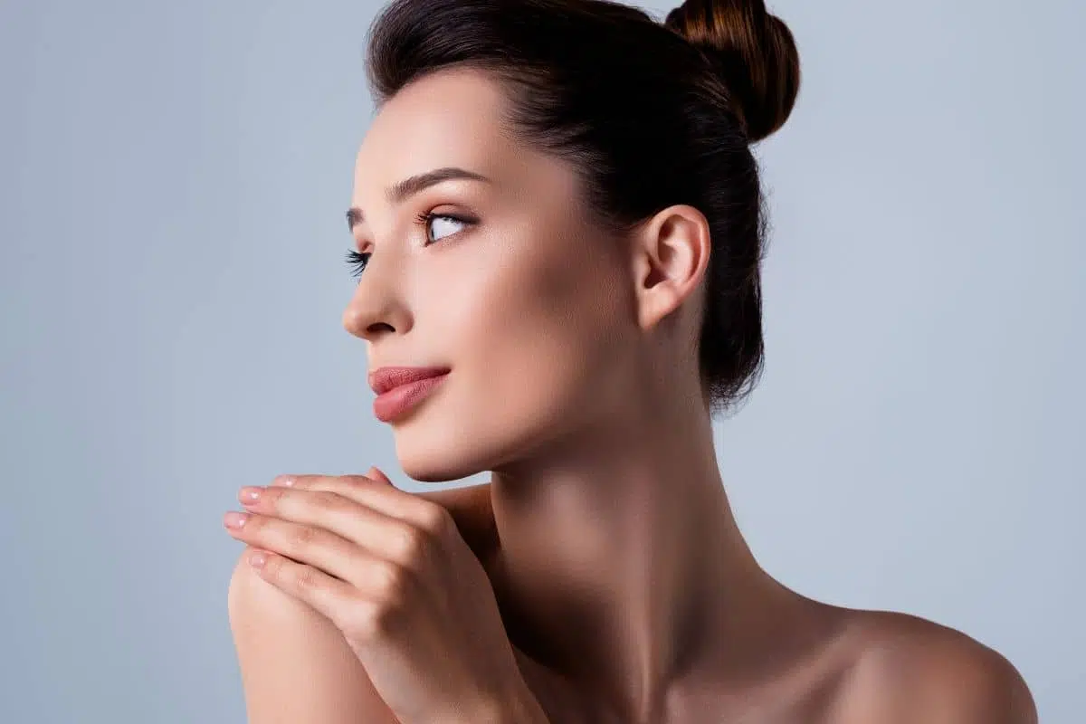 Elegant woman with flawless skin gazing sideways, symbolizing beauty and confidence after rhinoplasty surgery.