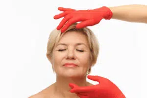 Mature woman with eyes closed receiving facial assessment before deep plane facelift for long-lasting rejuvenation.
