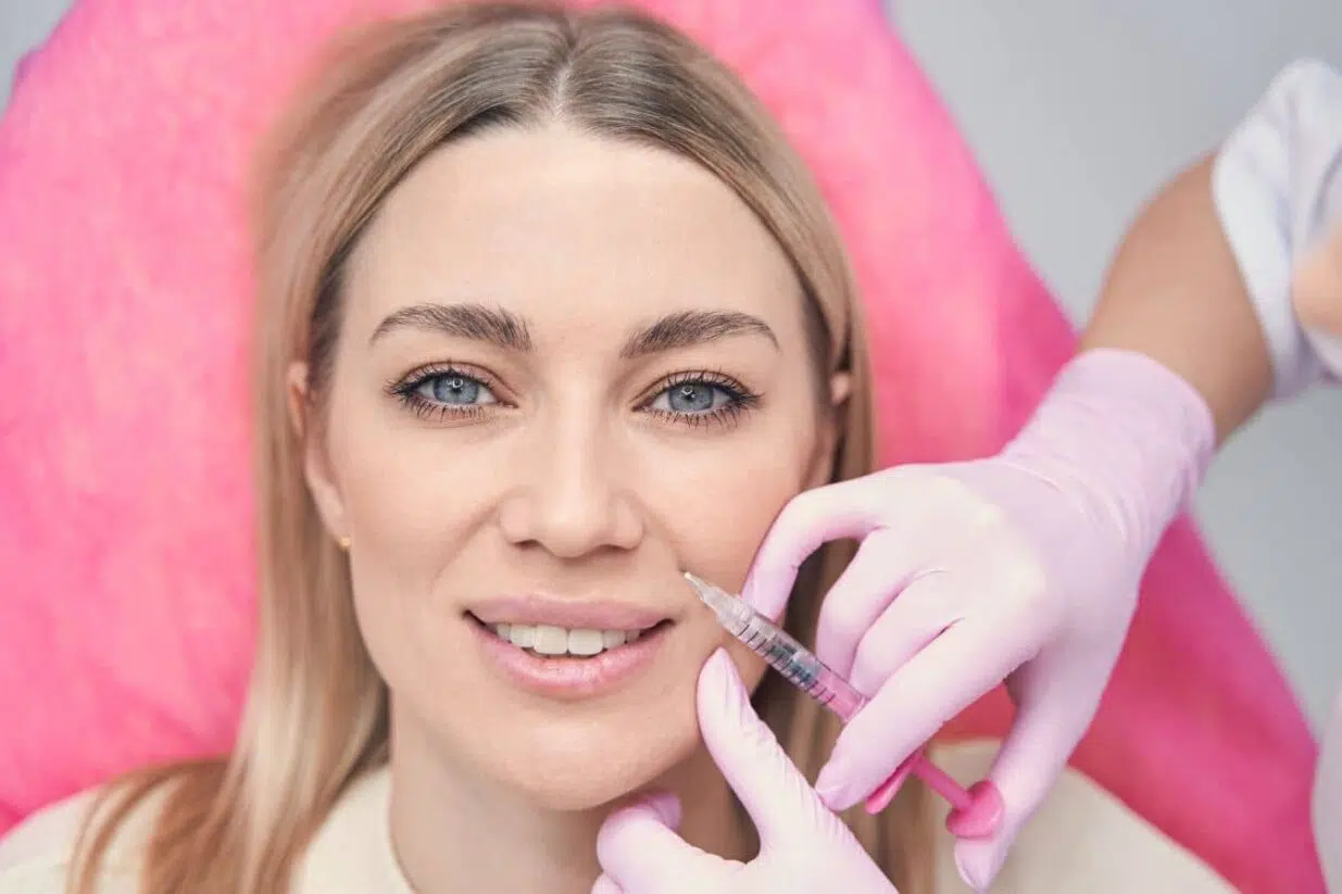 Patient receiving dermal filler injection near smile lines, highlighting non-surgical treatment for nasolabial folds